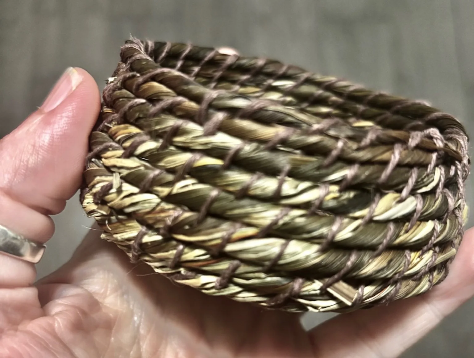 Hands holding a small woven natural fibre basket